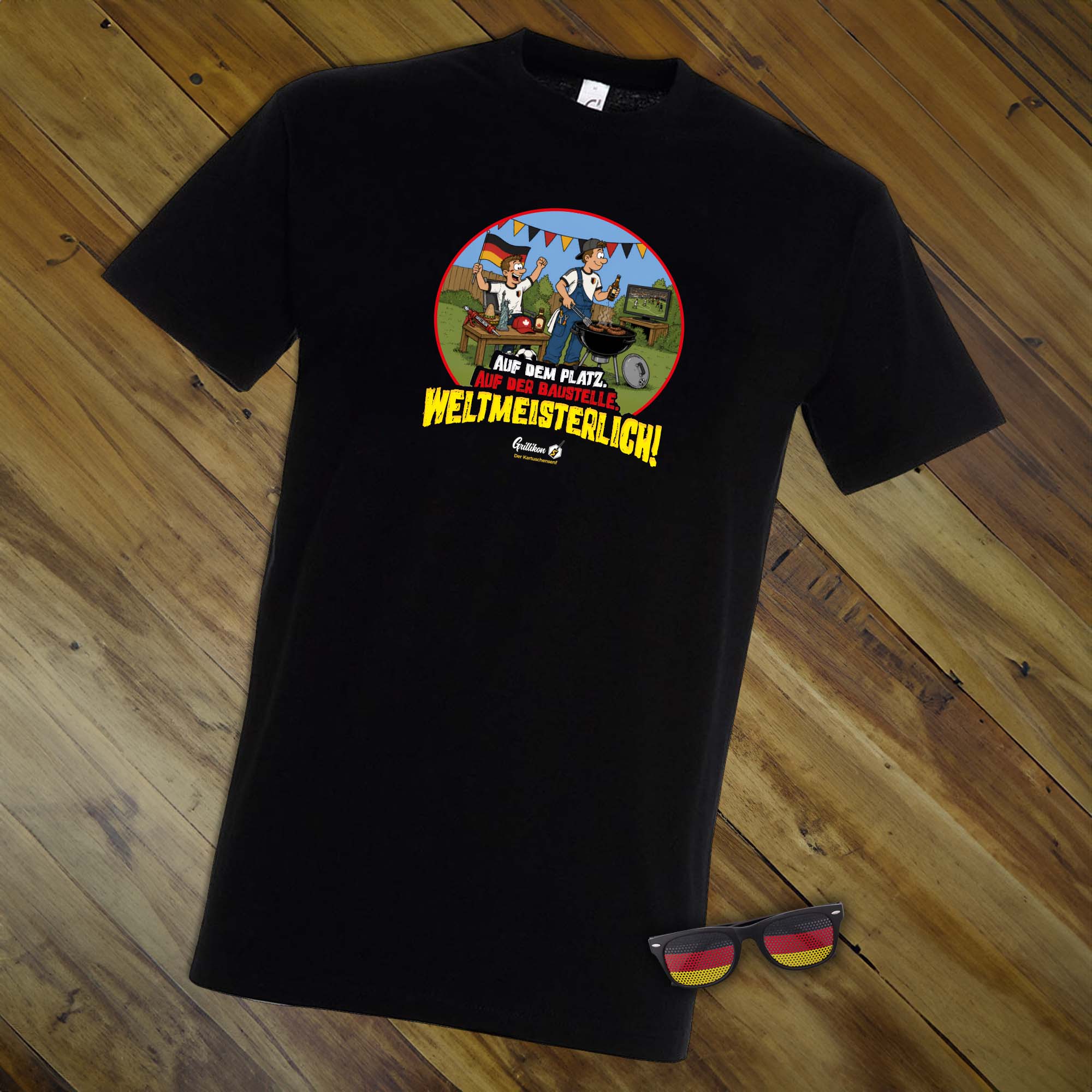 Schwarzes WM-T-Shirt aus dem Grillikon Geschenkset „WM-Edition“ mit Grillmotiv, Fußballszene und Slogan sowie Deutschland-Fanbrille