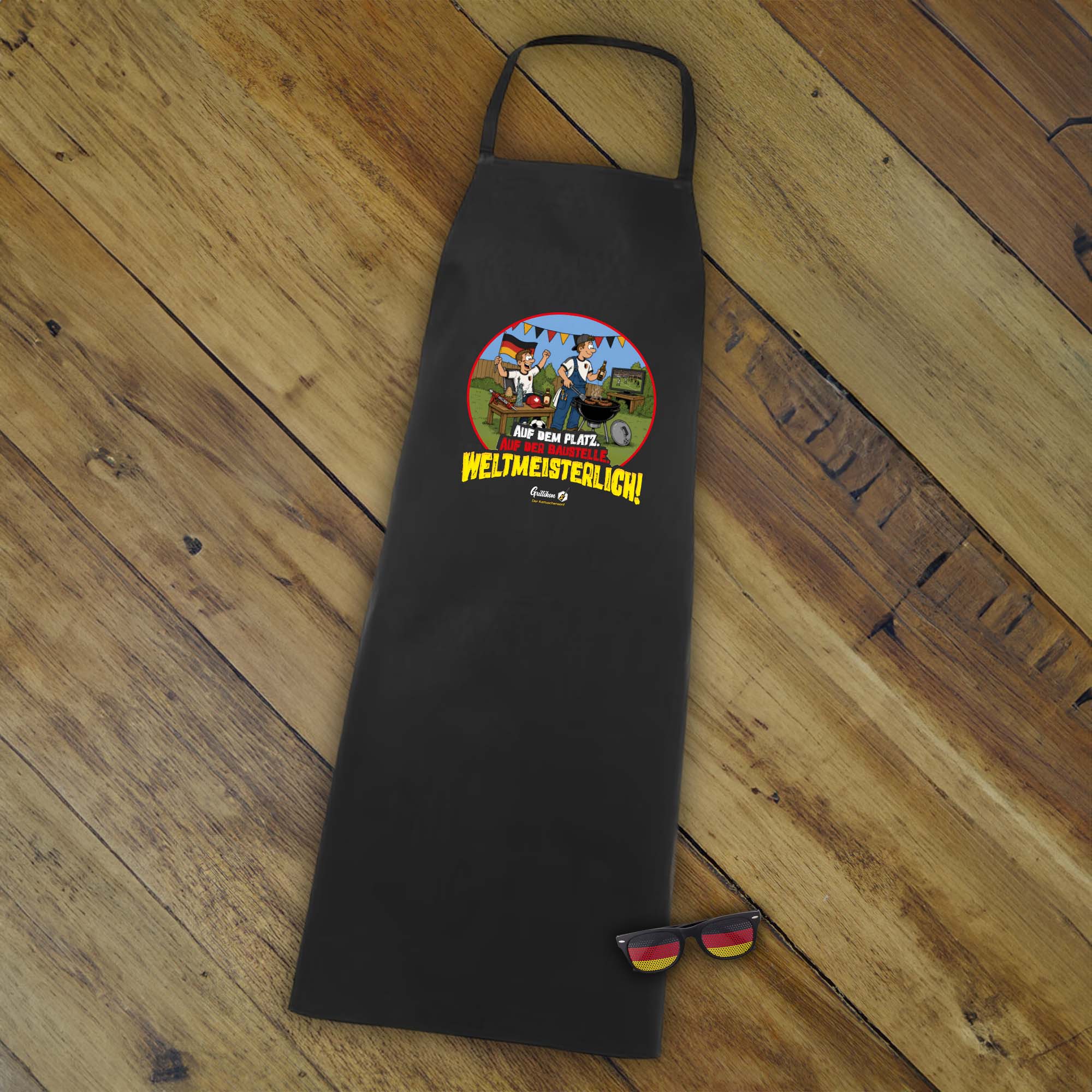 Schwarze Grillikon Grillschürze aus dem Geschenkset „WM-Edition“ mit Fußball-Fanmotiv und Deutschland-Fanbrille, passend zum 3x Mix in 300-ml-Kartuschen im Geschenkkarton