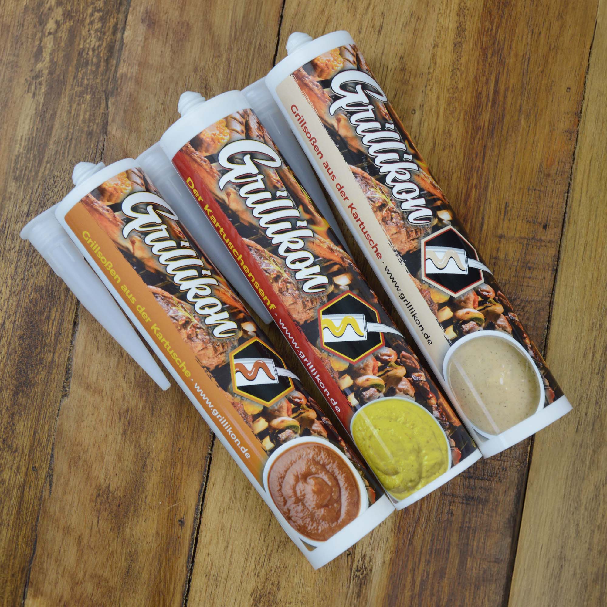 Drei Grillikon Saucenkartuschen mit Kartuschensenf und Grillsoßen auf einem Holztisch